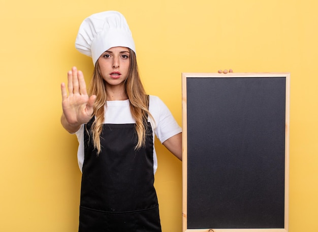 Mujer chef que parece seria mostrando la palma abierta haciendo un gesto de parada concepto de menú de pizarra