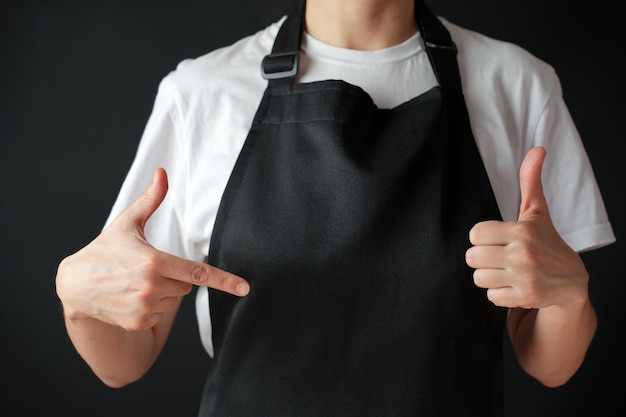 La mujer chef señala el delantal negro en primer plano