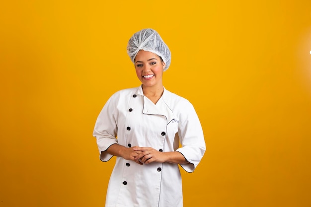 Mujer chef con uniforme y capó de pie con los brazos cruzados y posando sobre un aislado concepto de ocupación de fondo amarillo