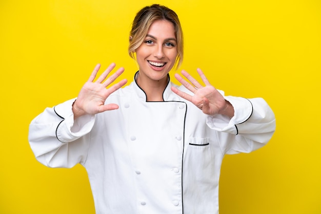 Mujer chef uruguaya aislada de fondo amarillo contando nueve con los dedos