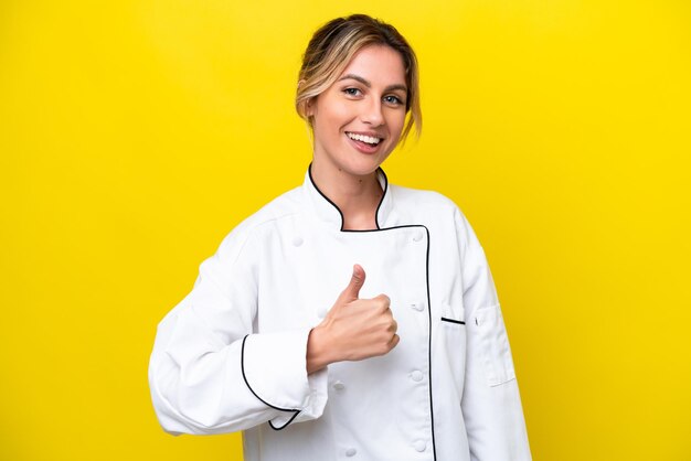 Mujer chef uruguaya aislada de fondo amarillo dando un gesto de pulgar hacia arriba