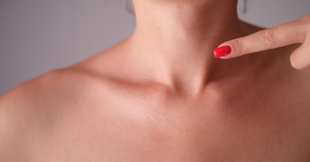 Foto una mujer chequea manualmente la glándula tiroidea en un primer plano del cuello