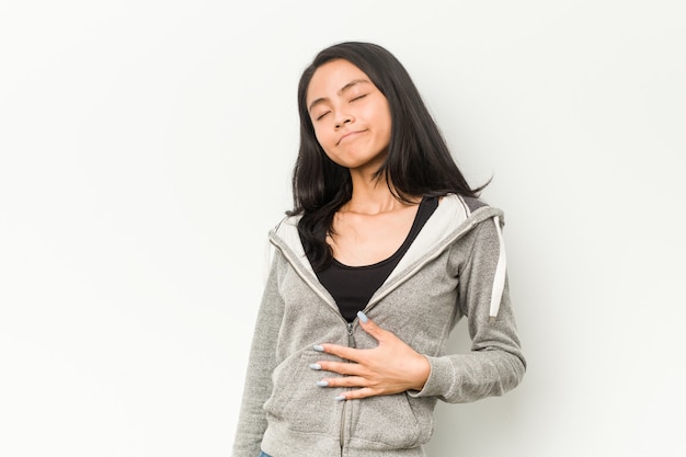 La mujer china de la aptitud joven toca la panza, sonríe suavemente, comiendo y concepto de la satisfacción.