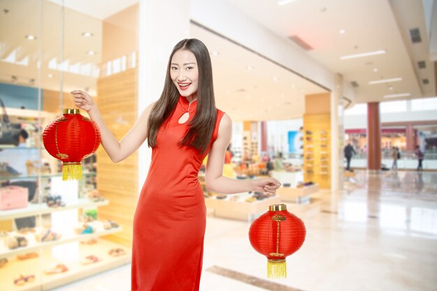 Mujer china asiática en un vestido cheongsam con linterna china