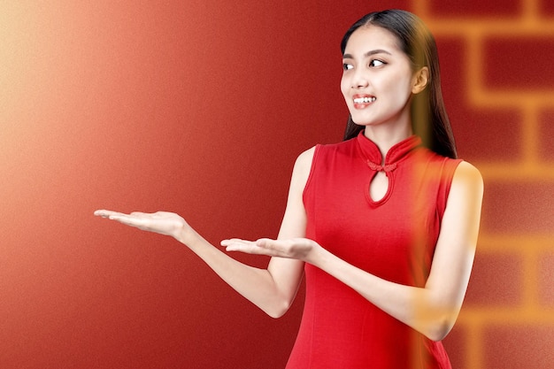 Mujer china asiática con un vestido cheongsam con la palma abierta que muestra algo con un fondo de color. Feliz Año Nuevo Chino