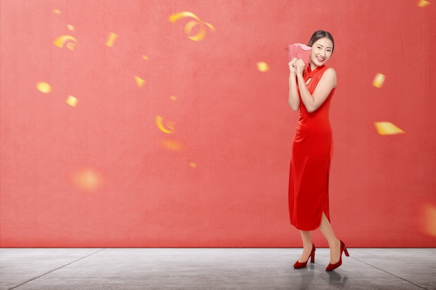 Mujer china asiática en un vestido cheongsam con sobres rojos