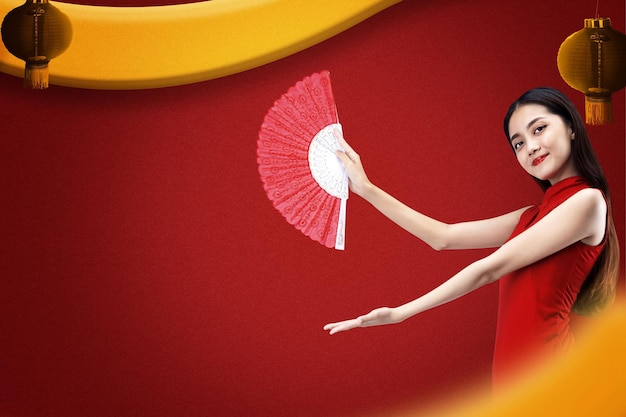 Mujer china asiática con un vestido cheongsam sosteniendo un abanico con la palma abierta mostrando algo con un fondo de color. Feliz Año Nuevo Chino