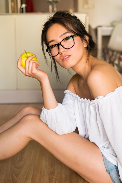 Mujer china comiendo una manzana sola en casa