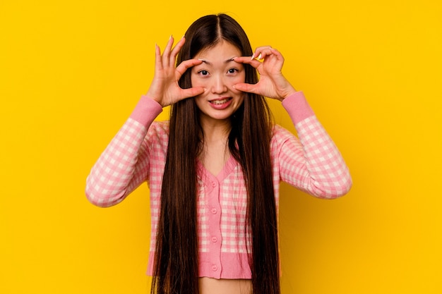 Foto mujer china joven aislada en amarillo manteniendo los ojos abiertos para encontrar una oportunidad de éxito.