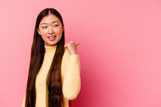 Mujer china joven aislada en puntos de pared rosa con el dedo pulgar lejos, riendo y despreocupada.