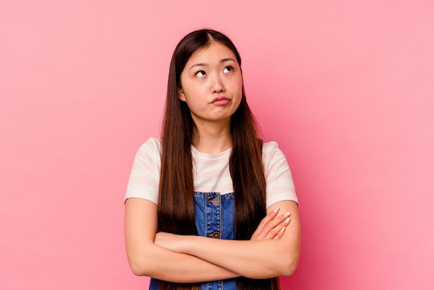 Mujer china joven aislada en rosa cansada de una tarea repetitiva.