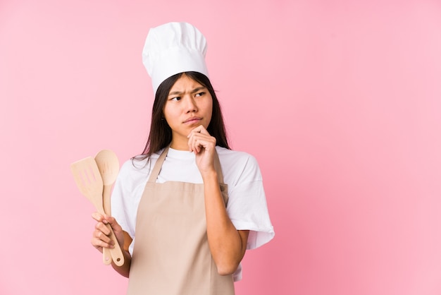 La mujer china joven del cocinero aisló mirar de lado con la expresión dudosa y escéptica.