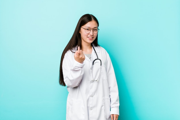 La mujer china joven del doctor que señala con el dedo en usted como invitando se acerca.