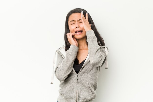 Mujer China joven fitness lloriqueando y llorando desconsoladamente.