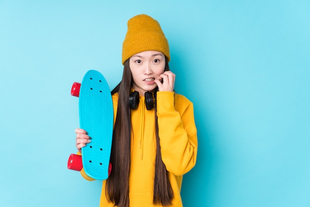 La mujer china joven del patinador aisló morderse las uñas, nervioso y muy ansioso.