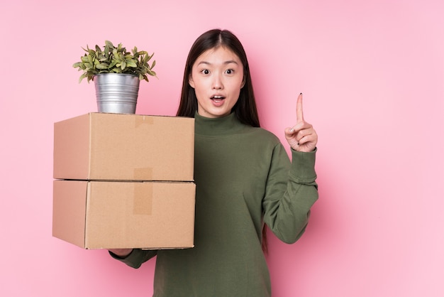 Mujer China joven sosteniendo cajas aisladas con una gran idea, concepto de creatividad.