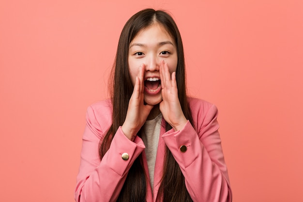 La mujer china del negocio joven que llevaba el traje rosado que grita excitó al frente.