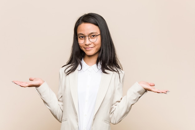 Mujer China de negocios joven que muestra una expresión de bienvenida.