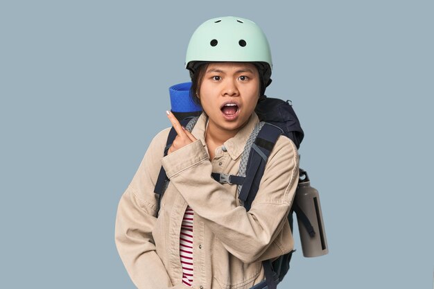 Mujer china preparada para actividades de montaña apuntando hacia el lado