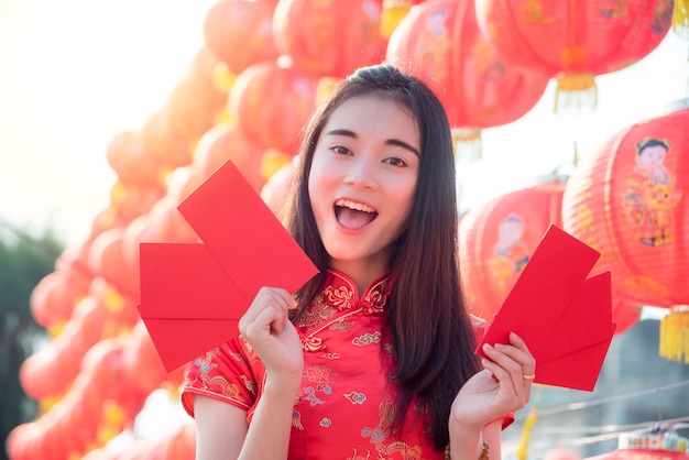 Mujer china con vestido tradicional sosteniendo un sobre rojo con cara feliz Concepto de año nuevo chino