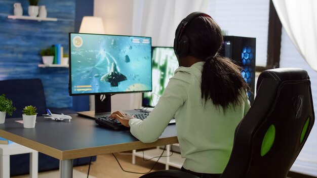 Mujer cibernética africana pro hablando con los jugadores en auriculares y ganando la competencia de videojuegos