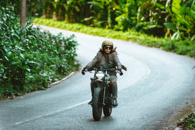 Mujer ciclista conduciendo una moto cafe racer