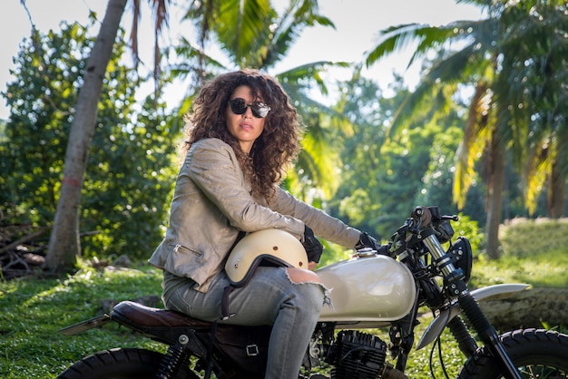 Mujer ciclista conduciendo una moto cafe racer