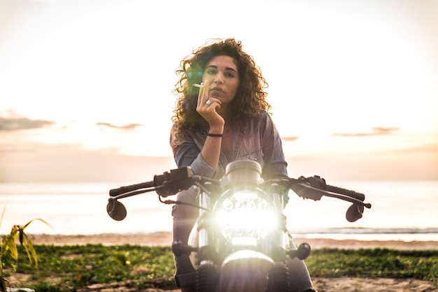 Mujer ciclista conduciendo una moto cafe racer