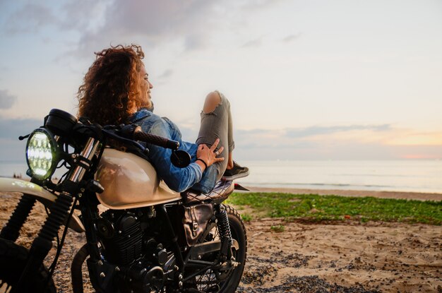 Mujer ciclista conduciendo una moto cafe racer