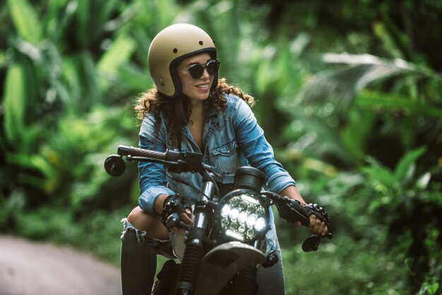 Mujer ciclista conduciendo una moto cafe racer