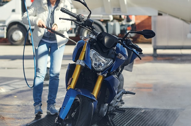 Mujer ciclista lavando su motocicleta