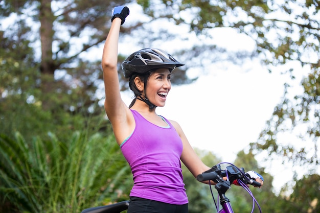 Mujer ciclista de pie con bicicleta de montaña en el parque