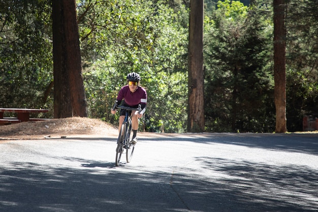 Mujer ciclista profesional a exceso de velocidad en una carretera en medio del concepto de Triatlón bosque