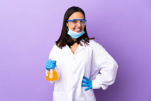 Mujer científica investigando una vacuna para curar la enfermedad posando con los brazos en la cadera y sonriendo