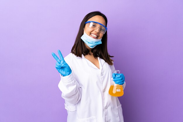 Mujer científica investigando una vacuna para curar la enfermedad sonriendo y mostrando el signo de la victoria