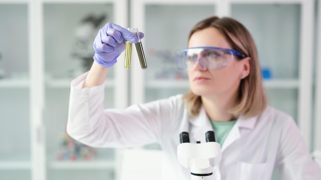 Mujer científica química comparando tubos de ensayo con aceite y combustible diesel contaminado en laboratorio