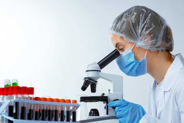 Mujer científico mirando a través de un microscopio en laboratorio