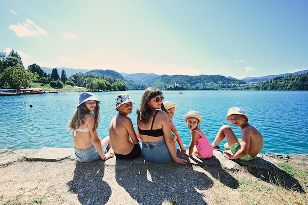 Mujer con cinco hijos sentarse en el muelle de vista hermoso lago Bled Eslovenia Madre de muchos hijos