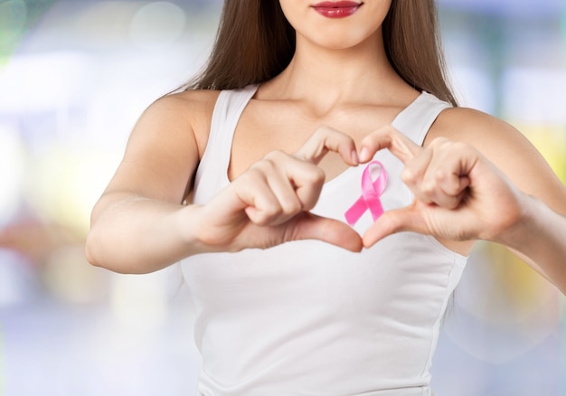 Foto mujer con cinta de cáncer de mama mostrando corazón