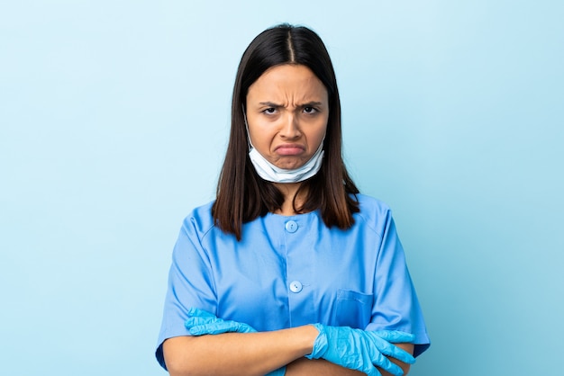 Mujer de cirujano sobre pared azul aislada con expresión infeliz