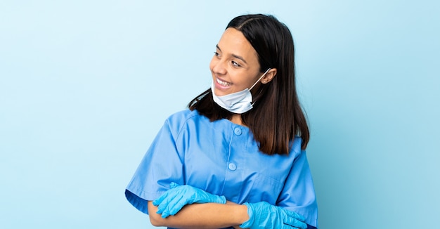 Mujer de cirujano sobre pared azul feliz y sonriente