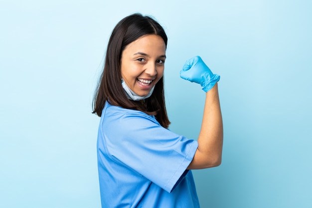 Mujer de cirujano sobre pared azul haciendo un gesto fuerte