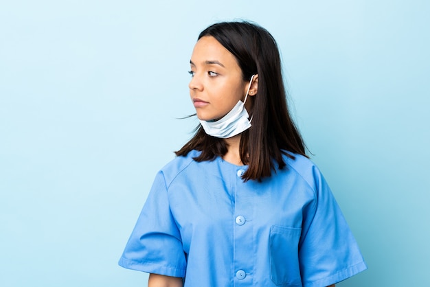 Mujer cirujano sobre pared azul mirando hacia el lado