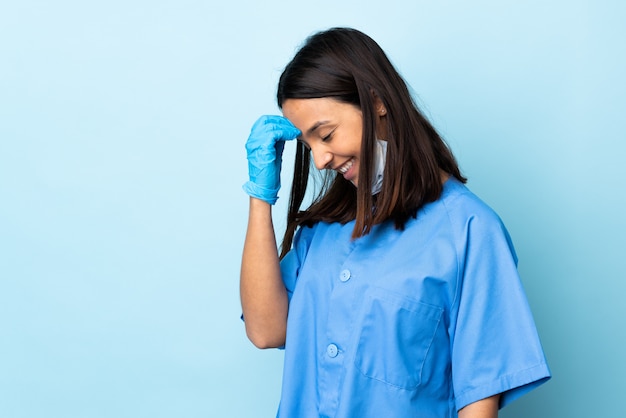 Mujer cirujano sobre pared azul riendo