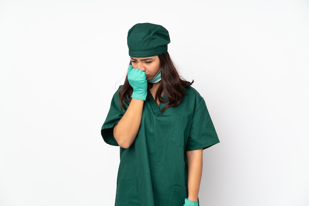 Mujer del cirujano en uniforme verde aislado en la pared blanca que tiene dudas