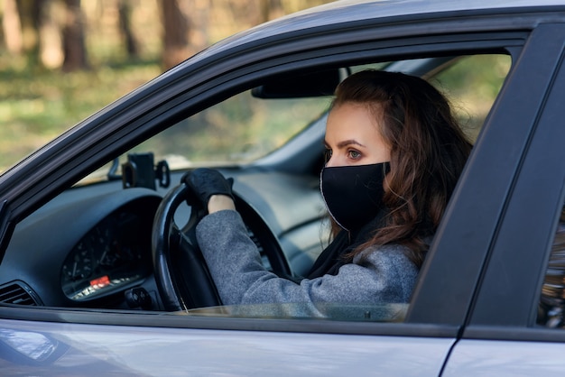 Mujer en la ciudad Persona en una máscara. Tema coronavirus. Mujer junto al auto.