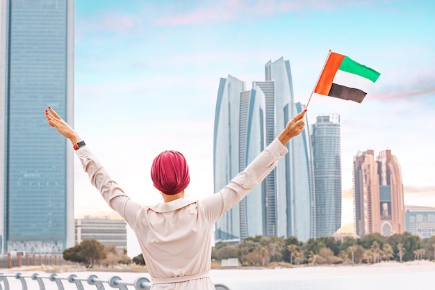 Mujer ciudadana de pie con la bandera de los Emiratos Árabes Unidos que ejemplifica los fuertes lazos culturales e históricos entre los EAU y sus países árabes vecinos