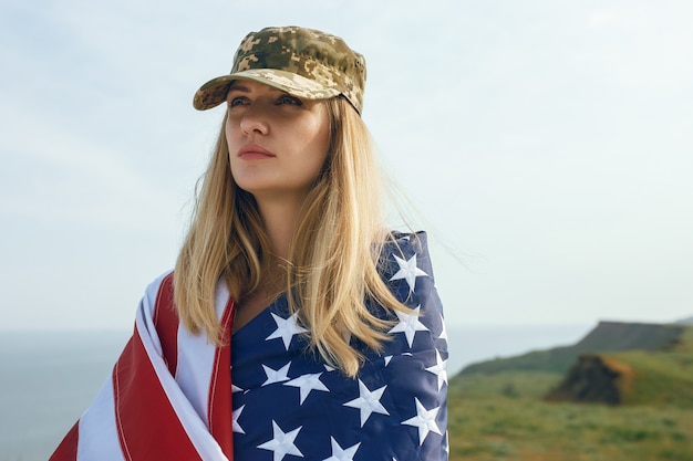 Mujer civil con gorra militar de su marido. una viuda con una bandera de los estados unidos se fue sin su marido. memorial day a los soldados caídos en la guerra. el 27 de mayo es un día conmemorativo.