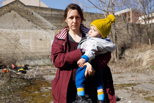 Mujer civil sosteniendo a su hijo entre las ruinas