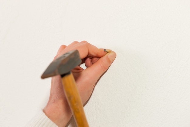 Foto la mujer está clavando un clavo en la pared